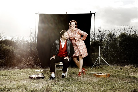 A man and woman smiling together with guitars by their sides