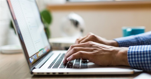 Photo of a person's hands typing on a laptop