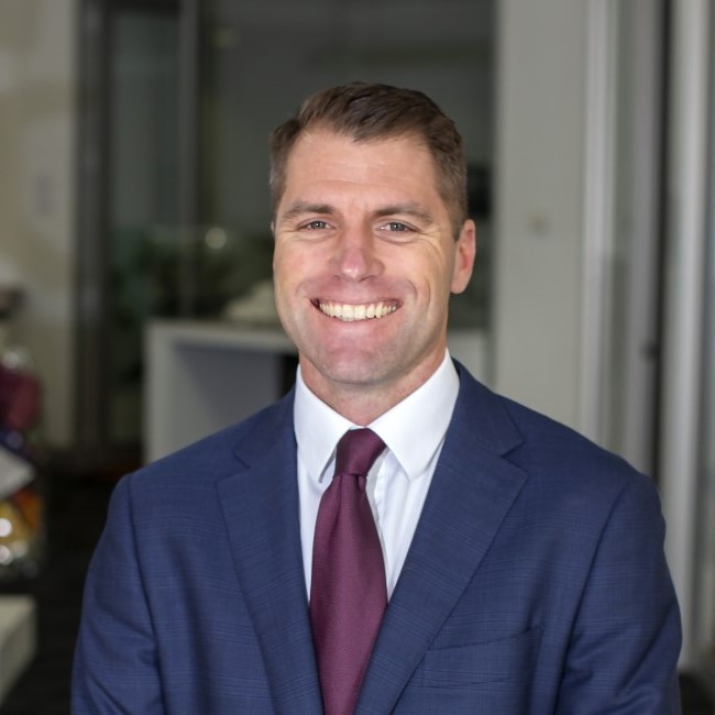 Photo of Hjalmar Philip. Hjalmar is wearing a suit and tie and standing in the foyer of the Nillumbik Council building.