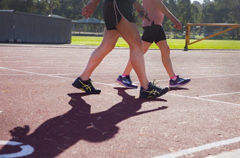 Photo of two people in sportswear walking across an athletics track