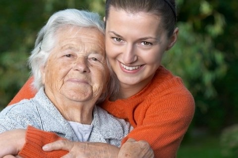 An image of an older woman and younger woman smiling at the camera