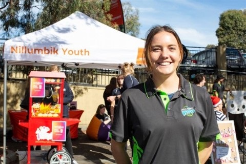 Photo of a girls smiling, standing in front of a gazebo that says 