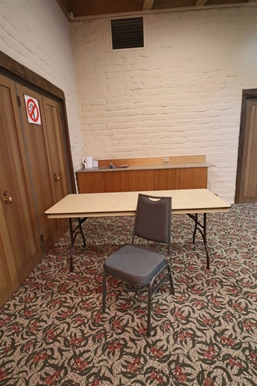 A table and padded chair in the corner of a carpeted room