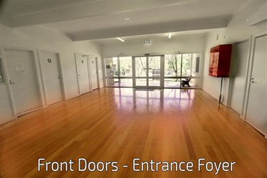A large light room with shiny timber floors and glass doors and windows filling the back wall