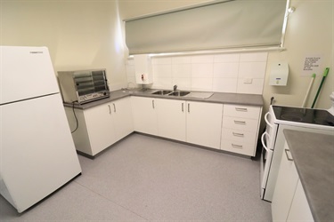 A kitchen with light cupboards, a fridge and freestanding stove and oven
