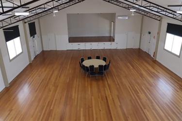 A large room with timber floorboards, and in the middle is a round table with chairs around it