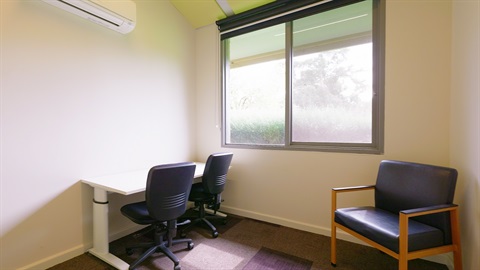 A meeting room with window, air conditioner, chairs and table