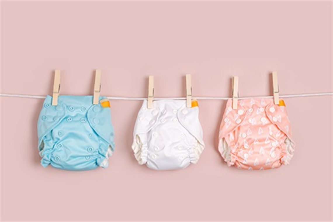 Colourful reusable nappies are hanging on a clothesline to dry