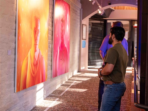 Visitors looking at two large paintings in our Midsumma Festival exhibition