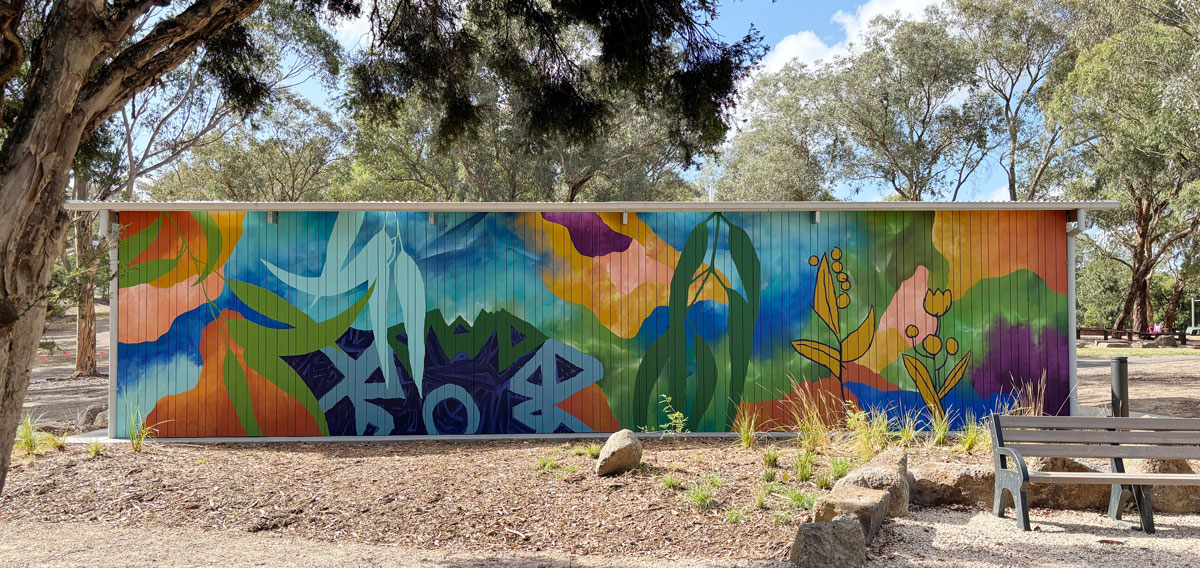A public building in a park is painted with large colourful abstract foliage