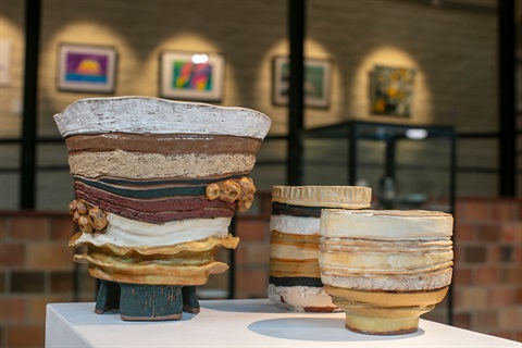 An image of three earthy coloured ceramic works on a plinth. 