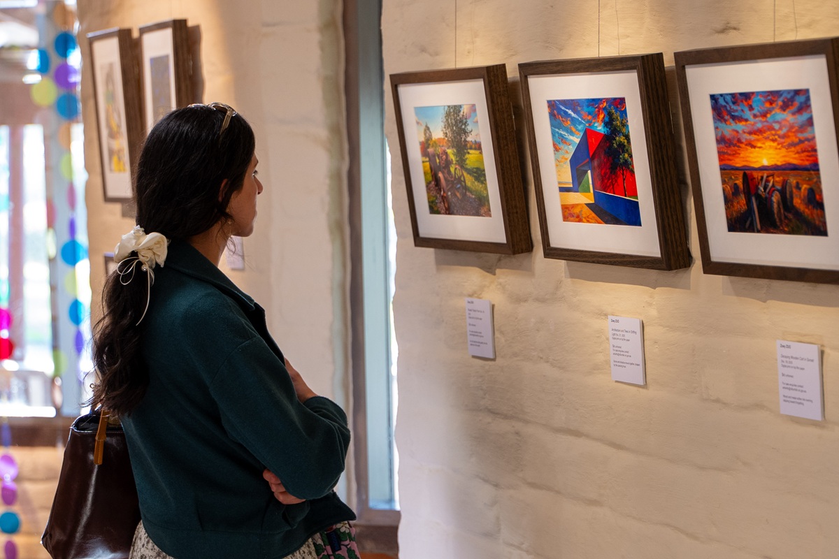 A women looking at three brightly coloured digital prints installed on the gallery wall