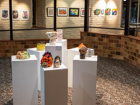 Sculptural works on white plinths in the middle of the room, two dimensional colourful paintings hung on the mud brick walls along the gallery ramp.
