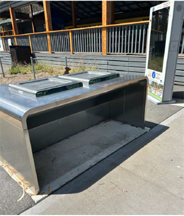 A stainless steel public barbeque on smooth concrete ground