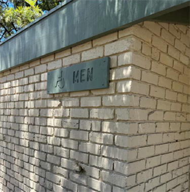 A brick building wall with a sign that says 'men'