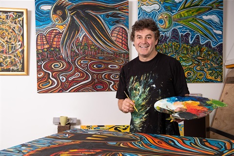 Artist Phillip HOWe in studio with paintings and easel