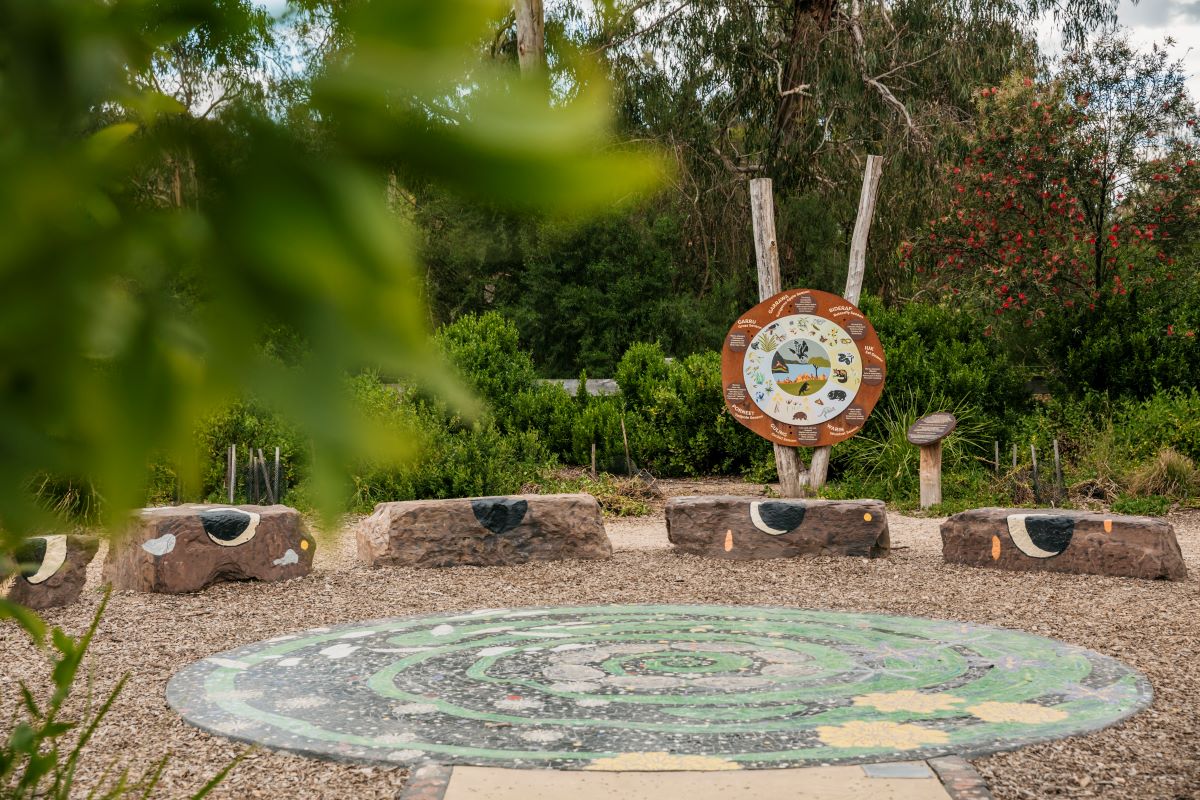 This is a photograph of the gathering circle and mosaic mural at the Eltham North Adventure Playground Wurundjeri Seasonal Garden.