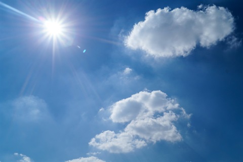 Photo of the sun in a blue sky with clouds