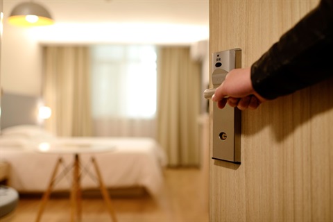 Photo of a person's hand opening a hotel room door