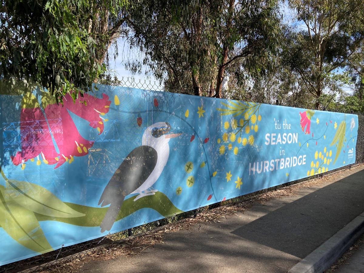 Photo of a fence covered in a promotional banner that reads 