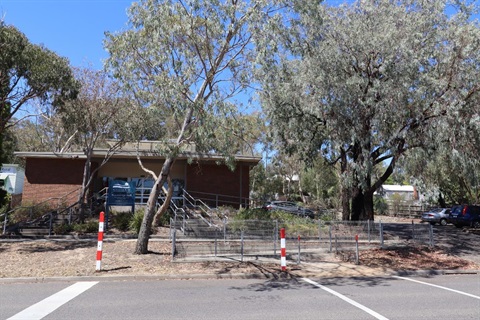 A brick building surrounded by trees with a Nillumbik Shire sign out the front