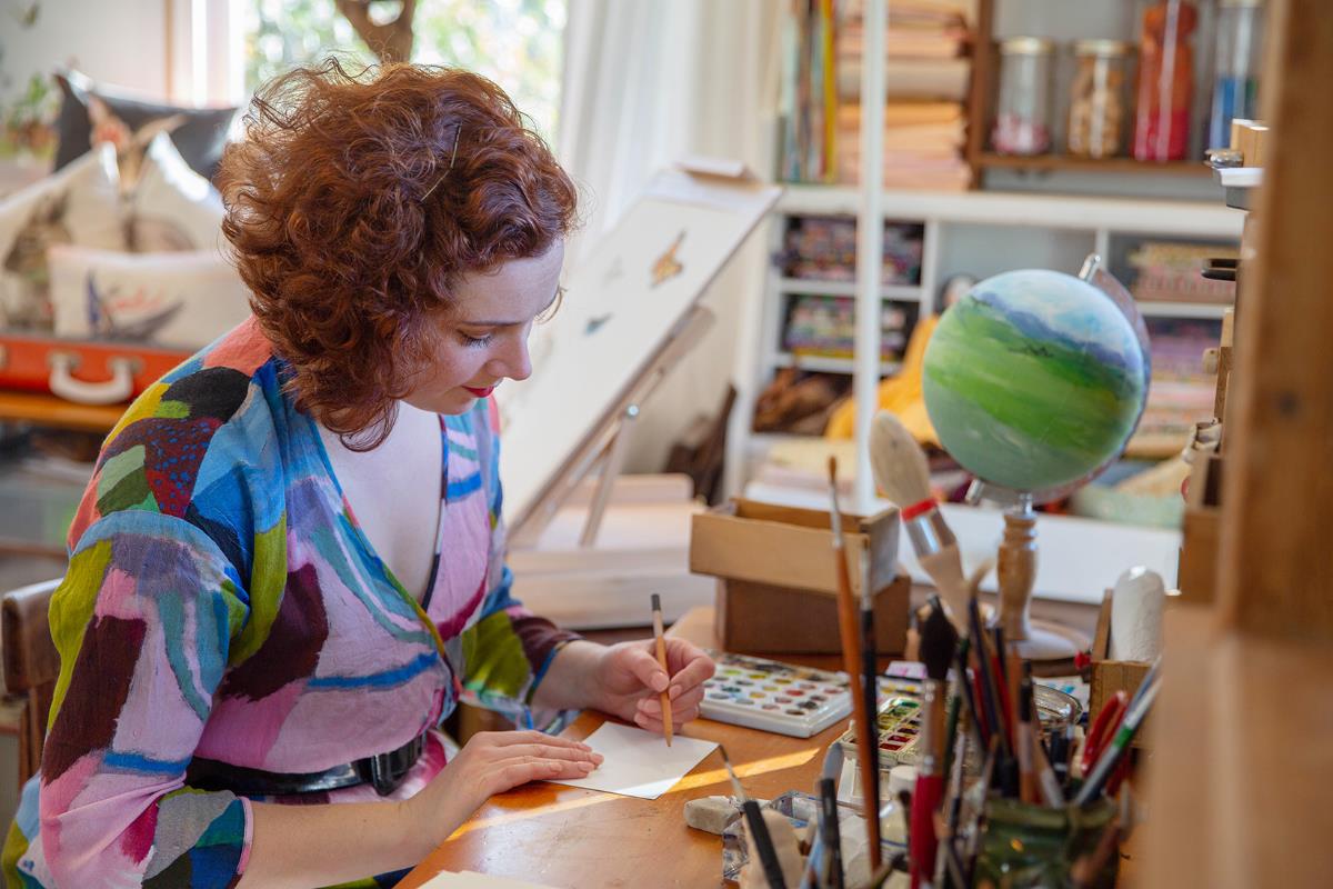 A woman is at a desk drawing