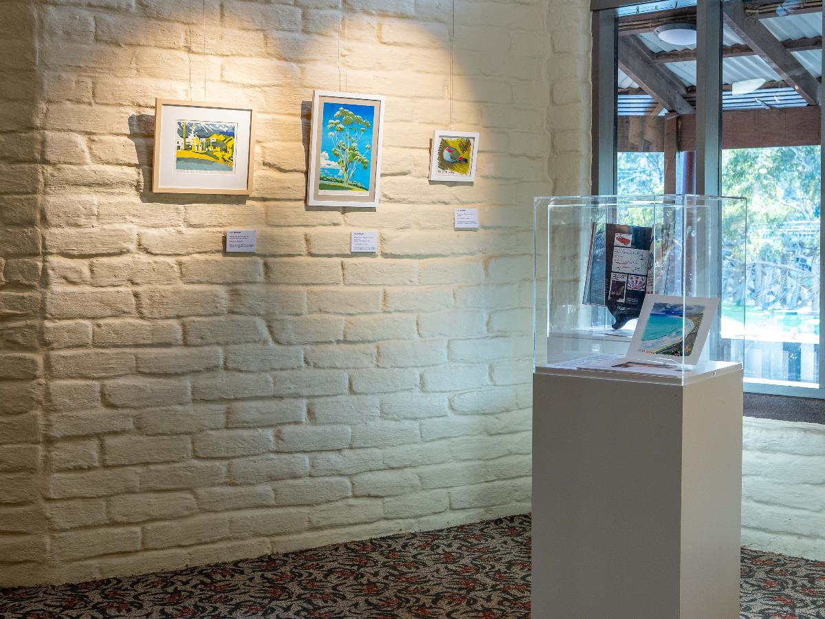 An image of three framed works and some items inside two plinths with perspex tops. The works are inspired by the local environment.